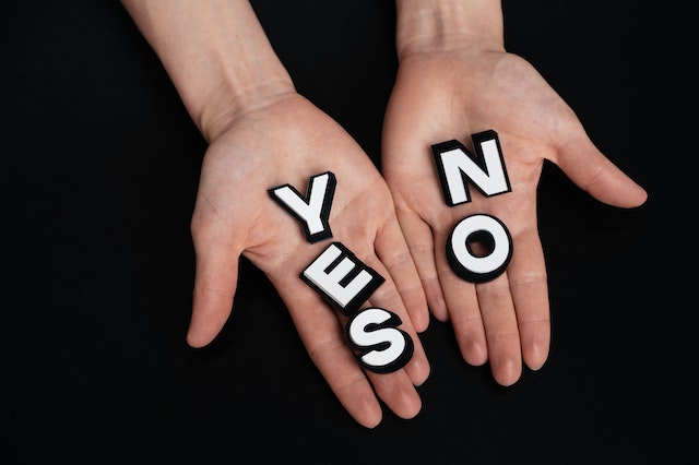 Dilema, jak se rozhodnout mezi dvěma muži, ruce drží odpovědi: yes or no