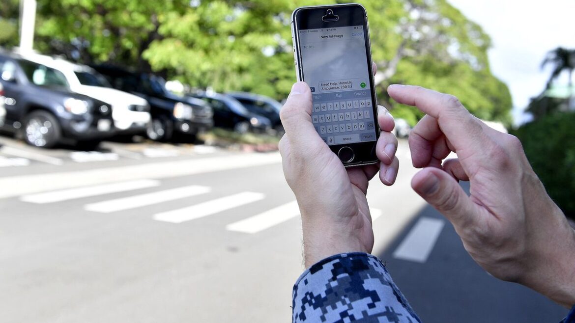 Ruka drží mobilní telefon venku u parkoviště