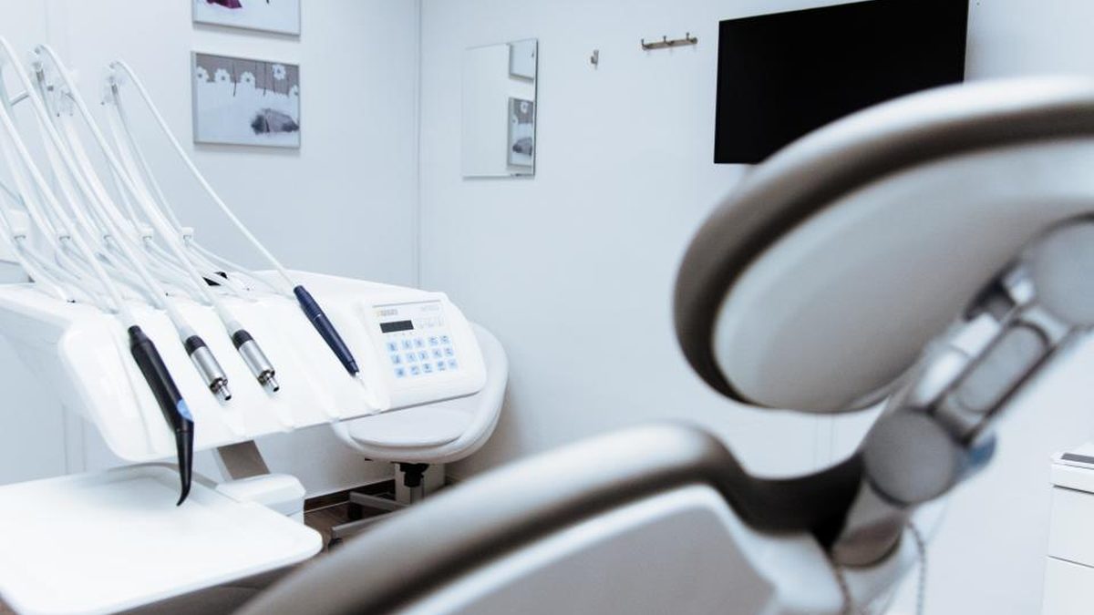 Zubní lékař vysvětluje pacientovi v křesle rozsah ošetření