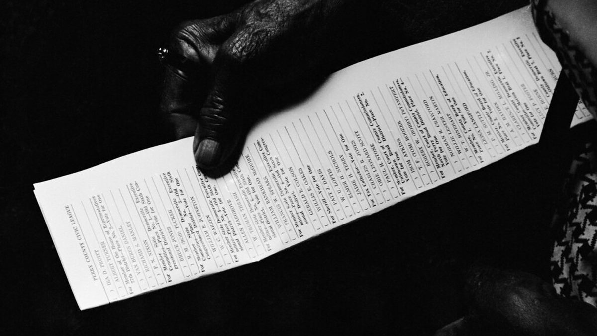 Ruka staršího člověka drží list s textem