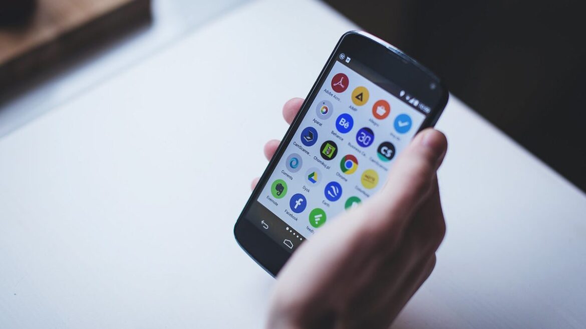 Ruka drží chytrý telefon s ikonami aplikací